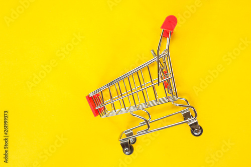 red shopping cart top view on yellow background.