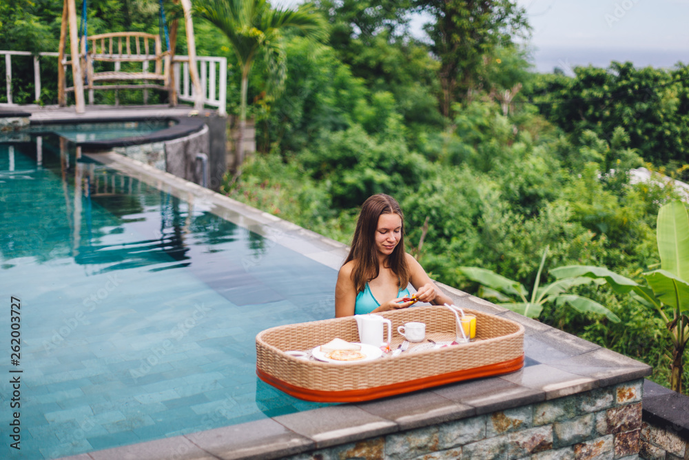 Girl eating floating breakfast in luxury infinity pool