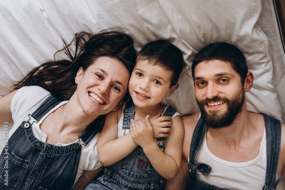 Happy family making selfie on bed. Close up. Parents spending free time with their son.