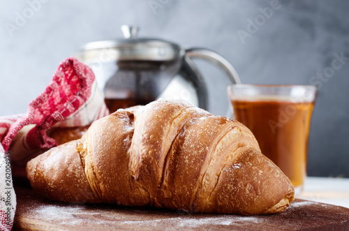 Fresh croissant with tea for breakfast. Food photography background.