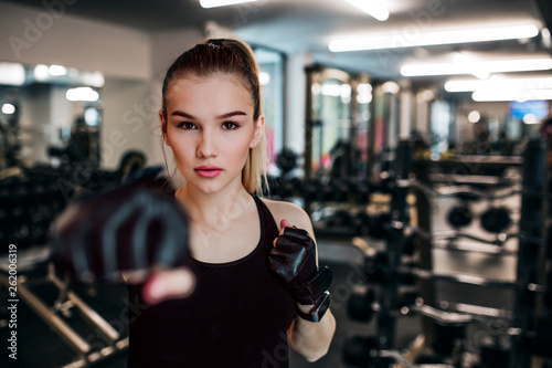 Young girl or woman with gloves, doing exercise in a gym.