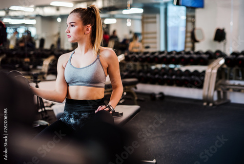 Young girl or woman with dumbbells, doing workout in a gym.