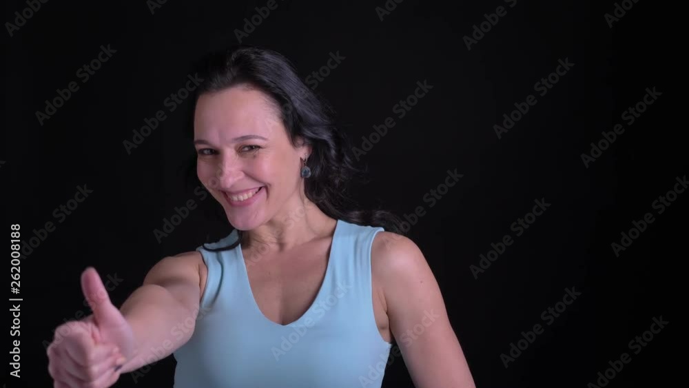Portrait of middle-aged woman demonstrating finger-up sign to show like and approvement on black background. Portrait of middle-aged woman demonstrating finger-up sign to show like and approvement on black background.