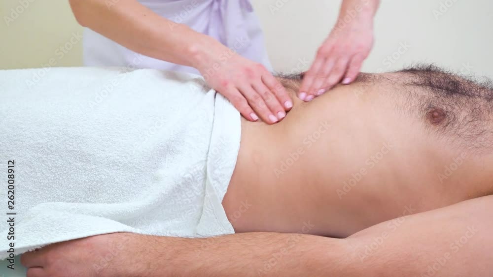 female hands massaging stomach of male patient in therapy room female hands massaging stomach of male patient in therapy room