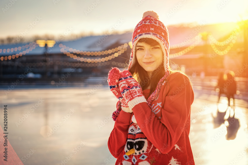 portrait of a young woman in a hat on the ice rink, a smile on his face, the sun