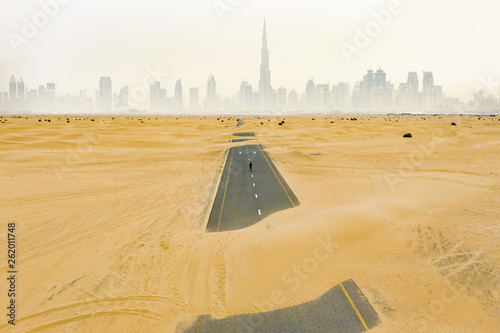 Canvas Print Stunning aerial view of an unidentified person walking on a deserted road covered by sand dunes in Dubai desert
