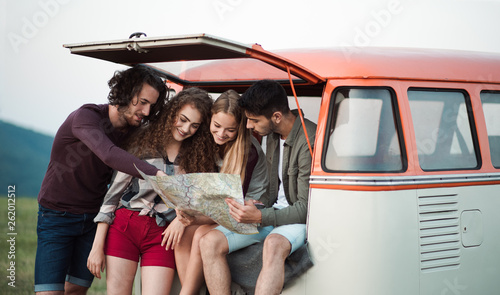 A group of young friends on a roadtrip through countryside, looking at map. © Halfpoint