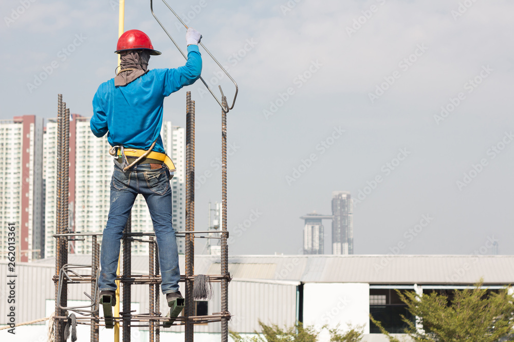 worker installing steel column on scaffolding in construction site