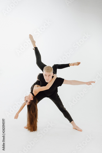 Modern Ballet Couple do Dance Lift on Middle Level. Male Dancer Hold Girl Upside Down. High Skill Perfomer in Black Denim and Top Isolated on White Background. Athletic Man Looking at Camera