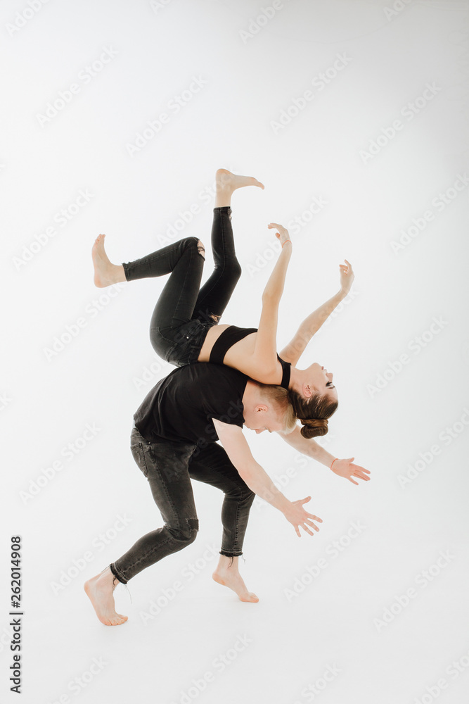 Obraz premium Talanted Dancing Couple Middle Level Lift Stunt. Contraction Spine Male Dancer Hold Girl on his Back. Beautiful Female Perfomer in Black Lay with Allonge Hand Isolated on White Background