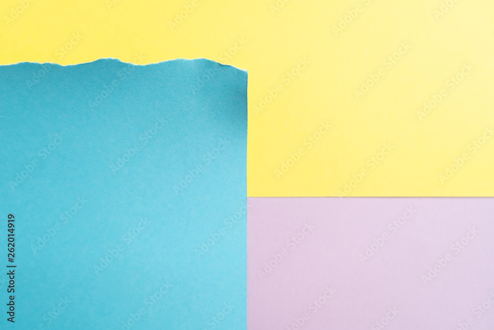 Purple-blue-yellow paper background. A piece of blue paper with torn edges on striped yellow and purple background 