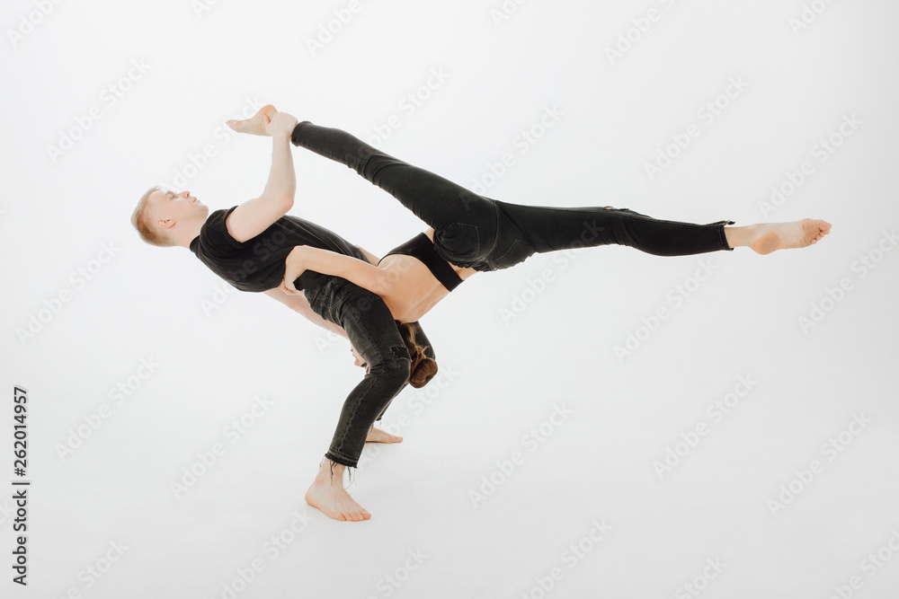 Caucasian Dancing Couple Middle Level Lift Stunt. Blond Man Dancer Hold Upside Down Girl. Beautiful Young Woman doing Side Split. Two Perfomer in Black Form Posing Isolated on White Background