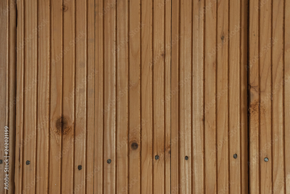 Orange wooden planks with frequent vertical gutter patterns cover the wall indoors. Wooden lining fastened with nails to the base. Orange wooden planks with frequent vertical gutter patterns cover the wall indoors. Wooden lining fastened with nails to the base.