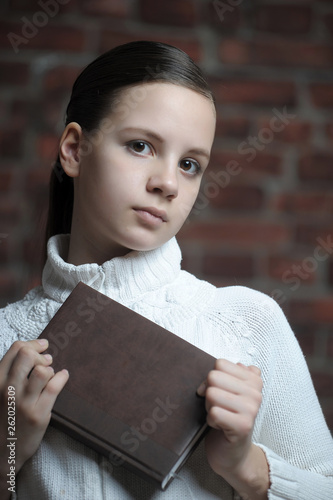 Teen girl pressed brown book to his chest