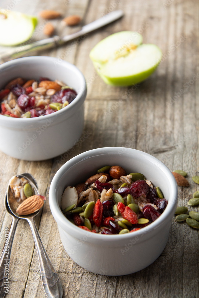 Healthy breakfast.Two bowls of muesli with oats, nuts and dried fruits - apples, resins, pumpkin seeds and almonds on wooden table. Top view. Rustic style. Healthy breakfast.Two bowls of muesli with oats, nuts and dried fruits - apples, resins, pumpkin seeds and almonds on wooden table. Top view. Rustic style.