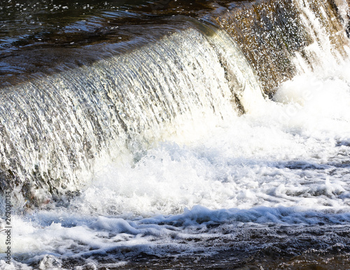 A small waterfall with falling water and a smooth water surface.