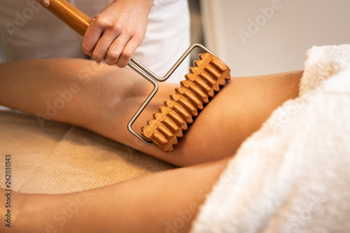 Close up of anticellulite massage with maderotherapy wooden rolling pin photo