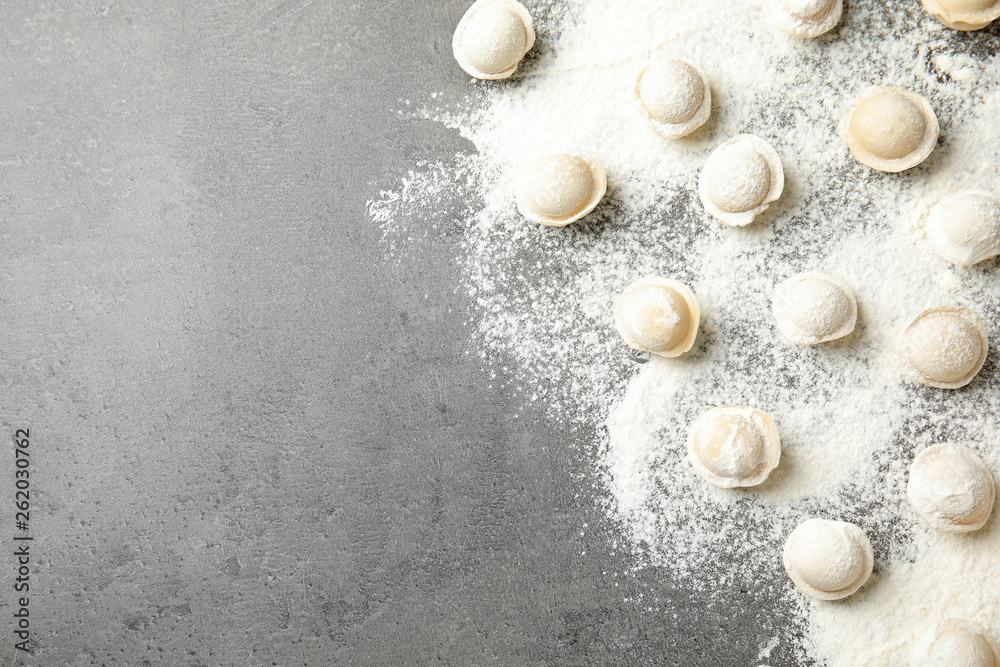 Raw dumplings on grey background, flat lay with space for text. Process of cooking