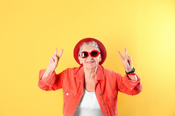 Portrait of cool grandmother on color background