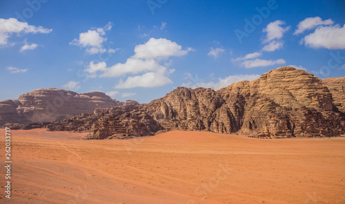 Wadi Rum Jordan Middle East panorama scenery desert landscape sand valley foreground and bare rocky mountain ridge background with vivid blue sky  travel planet and discovery  concept photography
