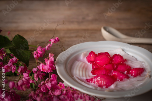 Cuadro en lienzo Thapthim krop, mock pomegranate seeds in coconut and syrup in the white bowl on the wood table there are flower and spoon placed around