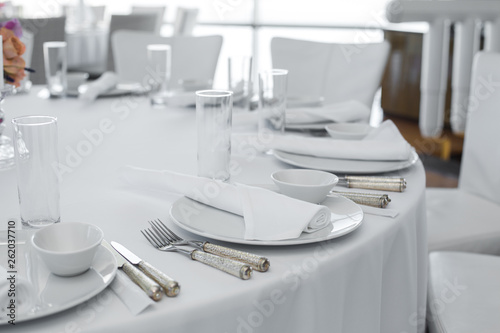 served table in the restaurant. clean white dishes layout on a white tablecloth