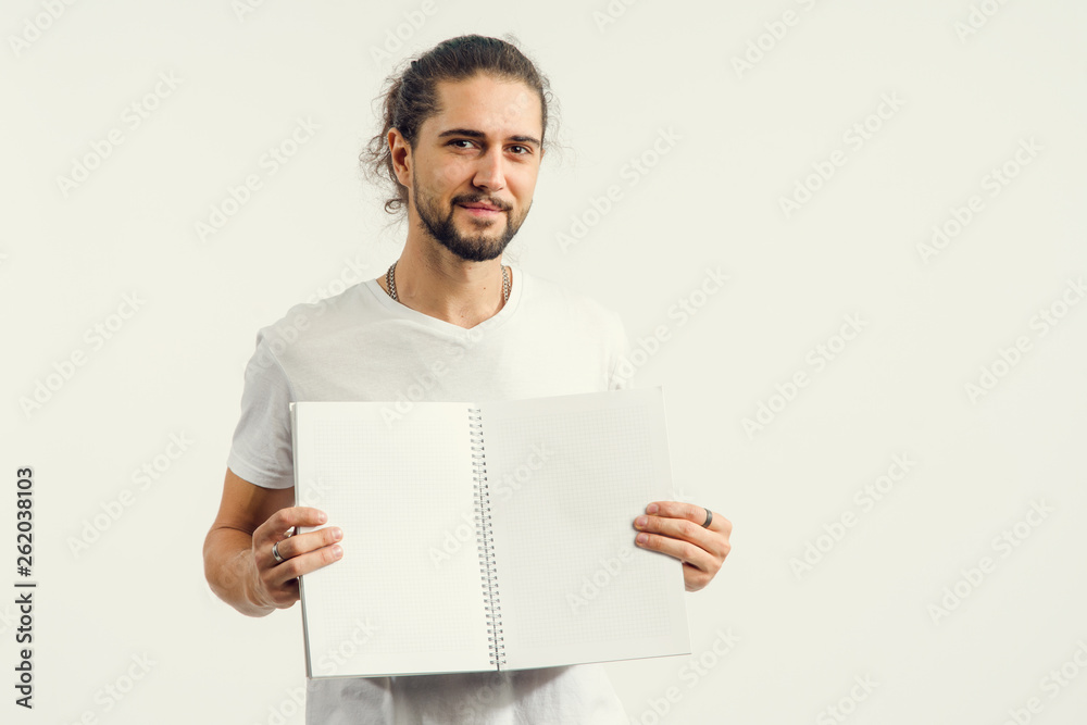 Young man with a beard shows an open notebook with clean pages. Place for text, concept for advertising tutorials. Young man with a beard shows an open notebook with clean pages. Place for text, concept for advertising tutorials.