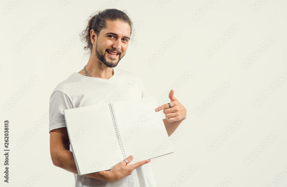 Young man with a beard shows an open notebook with clean pages. Place for text, concept for advertising tutorials. Young man with a beard shows an open notebook with clean pages. Place for text, concept for advertising tutorials.