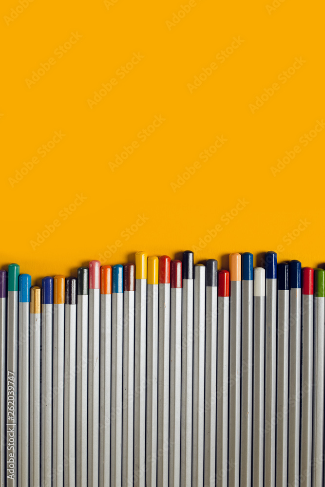 colored pencils arranged in a chaotic line on yellow background