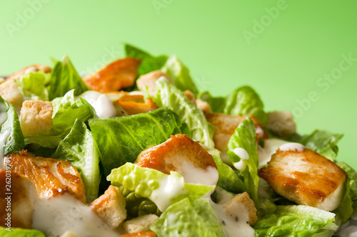 Caesar salad with lettuce,chicken and croutons on green background. Copyspace