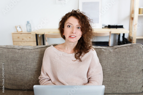 Young female student is afraid to read emai on laptop from the university with answer about the assessment of exam. Human facial expressions. Distance education photo