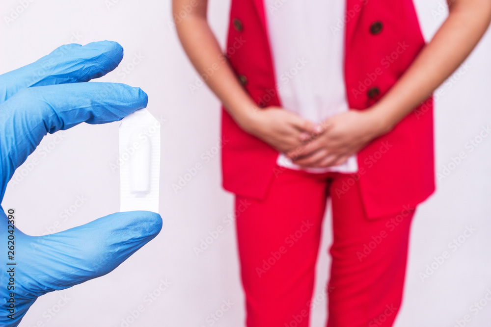 Doctor holds vaginal suppository suppository against the background of a girl who has pain and inflammation, urological infections, vaginal microflora, trichomoniasis