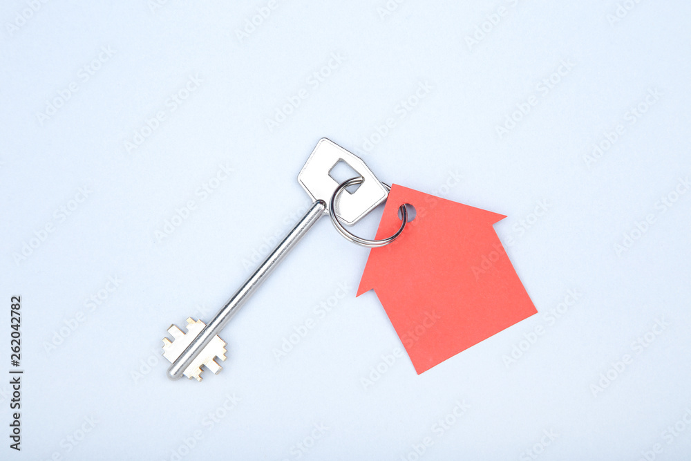 Silver key with paper house on grey background Silver key with paper house on grey background