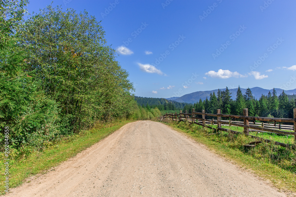country road in the mountains and a wooden fence