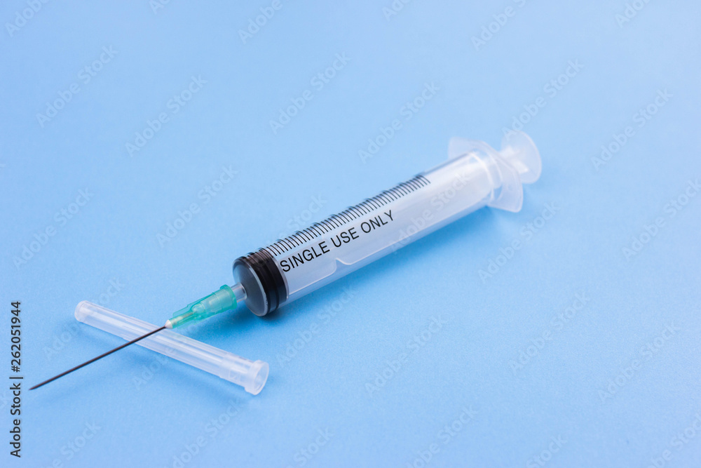 Disposable syringe and its packaging on a blue background Disposable syringe and its packaging on a blue background