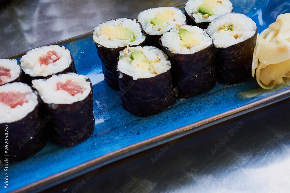 sushi rolls on a blue plate with vegetarian and salmon rolls on a silver table of the restaurant sushi rolls on a blue plate with vegetarian and salmon rolls on a silver table of the restaurant