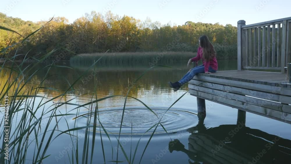 Young woman relaxes on lake pier. Young woman relaxes on lake pier.