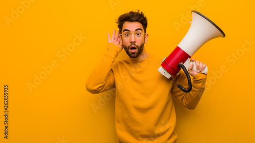Young man holding a megaphone try to listening a gossip photo