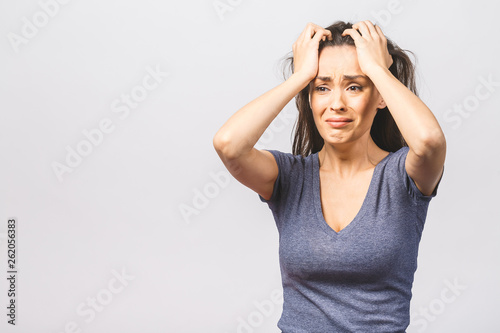 Studio shot of displeased European woman frowns face in discontent, cries from pain, wears casual, models over white studio wall. People, depression, negative feelings.