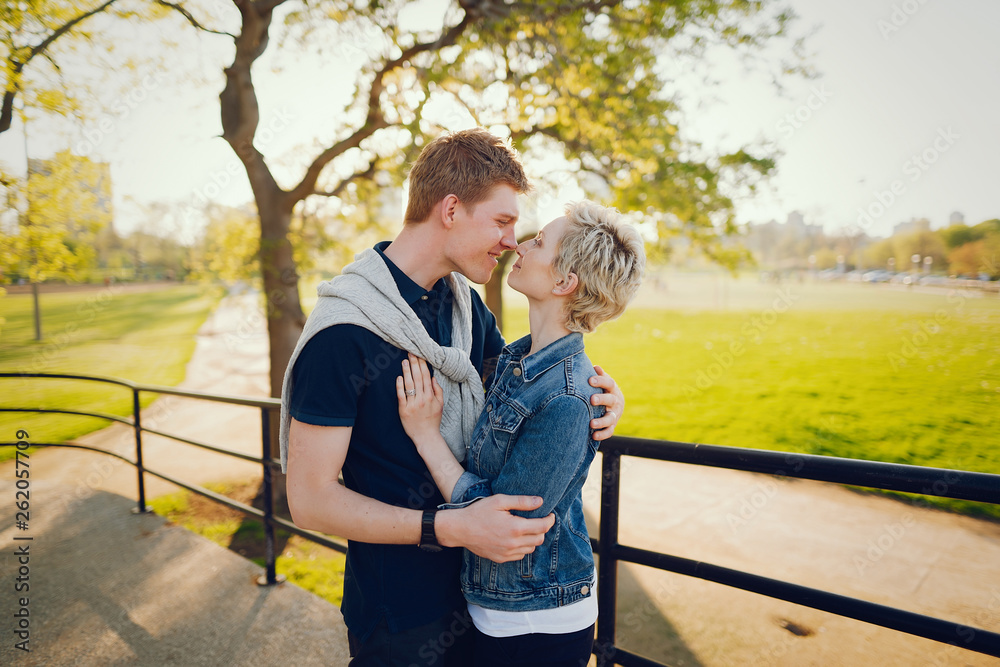 stylish and beautiful woman with short light hair, dressed in a blue jeans jacket walks with her handsome man in a sunny large city stylish and beautiful woman with short light hair, dressed in a blue jeans jacket walks with her handsome man in a sunny large city