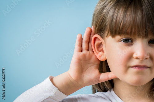  Toddler girl with hearing problem on light blue background. Close up, copy space.