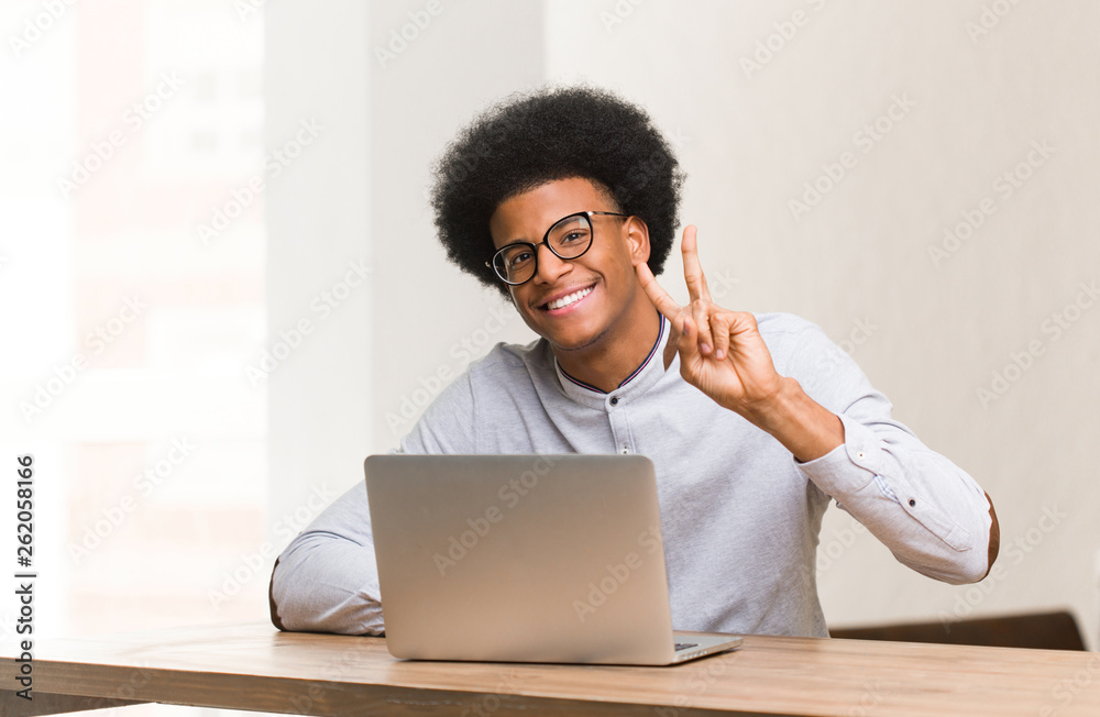 Young black man using his laptop doing a gesture of victory Young black man using his laptop doing a gesture of victory