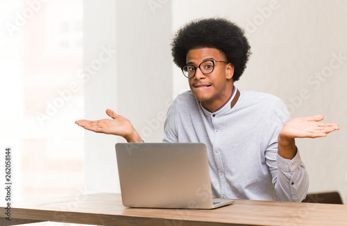 Young black man using his laptop confused and doubtful