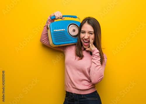 Young cute woman holding a vintage radio shouting something happy to the front photo