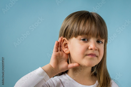 Little girl with hearing problem on light blue background. Close up, copy space.