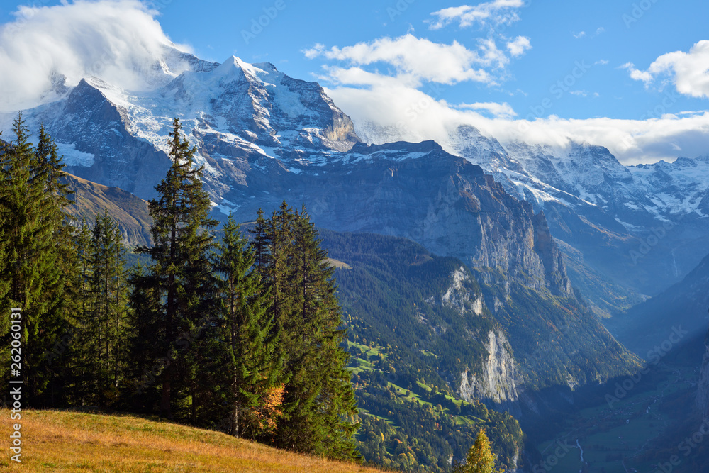 Mountains panorama at sunset with Jungfrau peak in the clouds and Lauterbrunnen valley in Switzerland.
