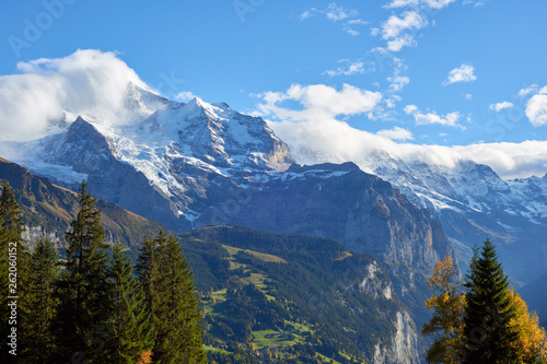 Mountains panorama at sunset with Jungfrau peak in the clouds and Lauterbrunnen valley in Switzerland.