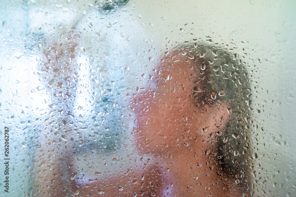 Fototapeta premium woman in the shower behind glass with drops