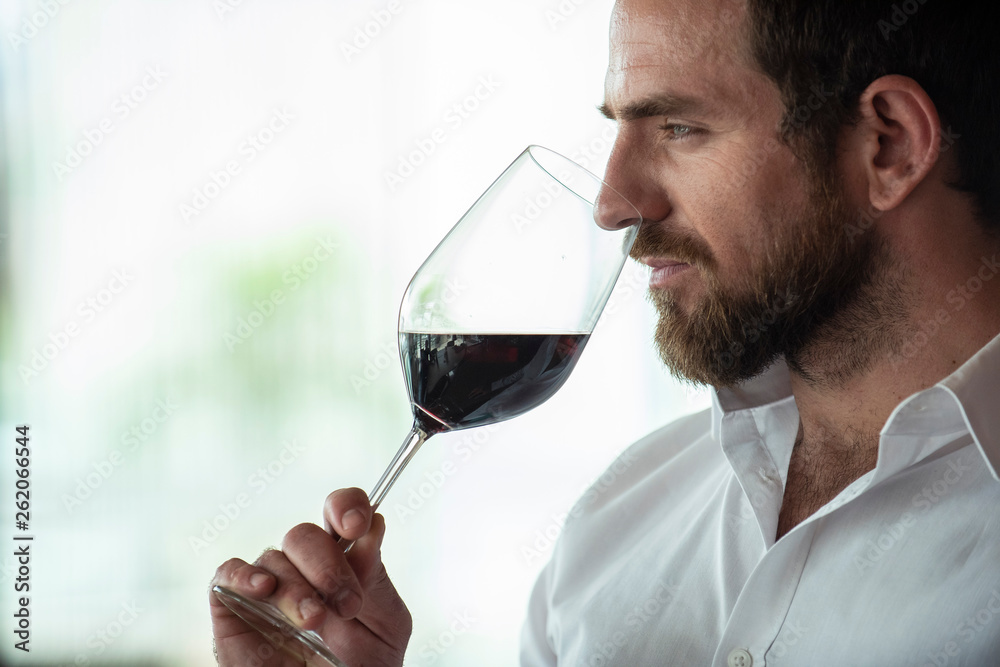 Thoughtful mid adult man smelling red wine in bar Thoughtful mid adult man smelling red wine in bar