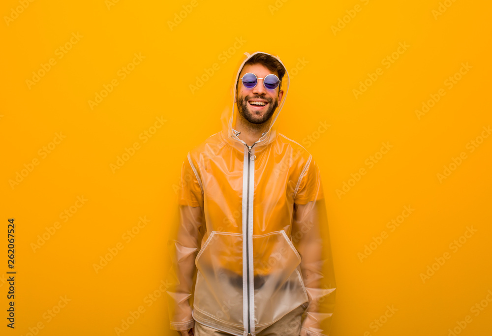 Young man wearing a rain coat cheerful with a big smile Young man wearing a rain coat cheerful with a big smile